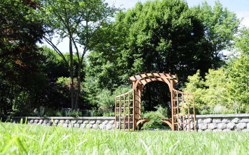 Stone retaining wall with wooden garden arbor